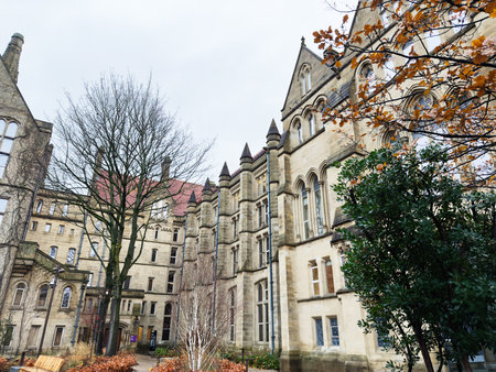 Manchester, UK - December 06, 2025: A historic stone building in Manchester features Gothic architecture, a courtyard, and bare trees in autumn.のeditorial素材