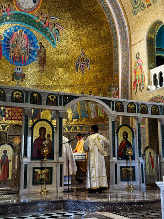 Rome, Italy - July 29, 2025: A sacred Orthodox service unfolds in a gold mosaicked sanctuary with...