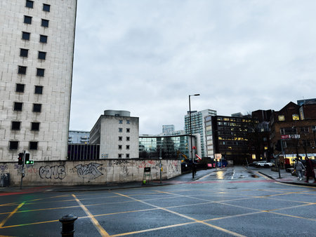 Manchester, UK - January 21, 2026: Overcast city street in Manchester with contemporary architecture and graffiti on a low wall.のeditorial素材