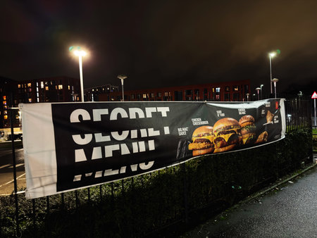 Manchester, UK - January 21, 2026: Night scene in Manchester with a large burger McDonalds banner advertising fast food under street lights.のeditorial素材