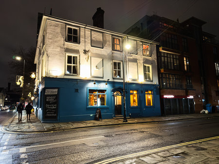 Manchester, UK - January 21, 2026: A white three-story building houses a cozy blue The Oxnoble pub at night in Manchester, with warm glowing windows and street lamplight.のeditorial素材