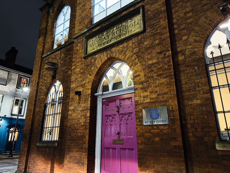 Manchester, UK - January 21, 2026: Brick St Matthew's Sunday School building in Duke St, Manchester with a purple door and glowing arched windows at night, urban street scene.のeditorial素材