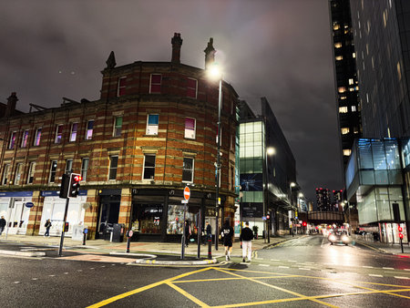 Manchester, UK - January 21, 2026: Night scene in Manchester shows a brick corner building beside modern glass offices and active traffic.のeditorial素材