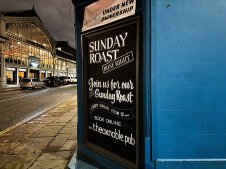 Manchester, UK - January 21, 2026: Chalkboard sign promotes Sunday roast outside a Manchester Oxnoble pub along a blue-walled street.のeditorial素材