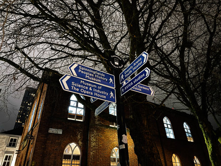 Manchester, UK - January 21, 2026: Blue signpost directions in Manchester guide viewers past brick buildings at night, creating urban, moody city vibes in Wellington Place.のeditorial素材