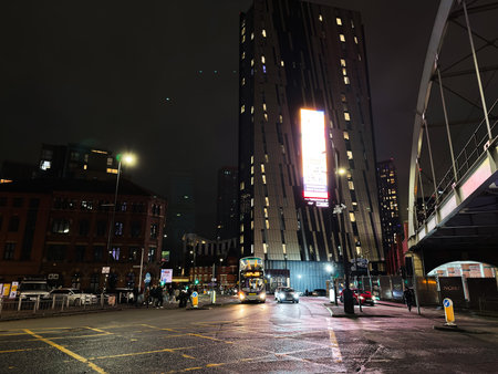 Manchester, UK - January 21, 2026: Nighttime urban mood in Manchester with a bright billboard, traffic, pedestrians and wet streets.のeditorial素材