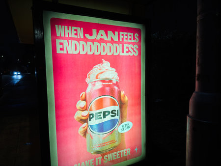 Manchester, UK - January 21, 2026: Nighttime Pepsi ad with whipped strawberries cream topping in vibrant pink colors, Manchester street scene.のeditorial素材