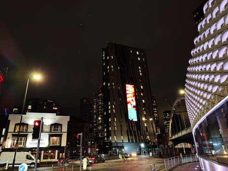 Manchester, UK - January 21, 2026: Night scene in Manchester with illuminated skyscrapers, traffic, and a historic pub beside a futuristic facade.のeditorial素材