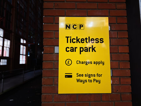Manchester, UK - January 21, 2026: Bright yellow NCP sign on brick wall in Manchester, guiding ticketless car park payments and signs.のeditorial素材