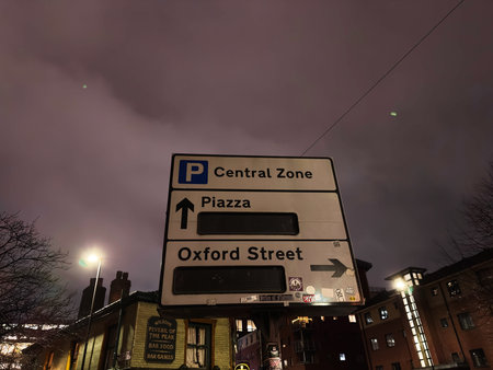Manchester, UK - January 21, 2026: Night city scene in Manchester with signs pointing to central zone and streets.のeditorial素材