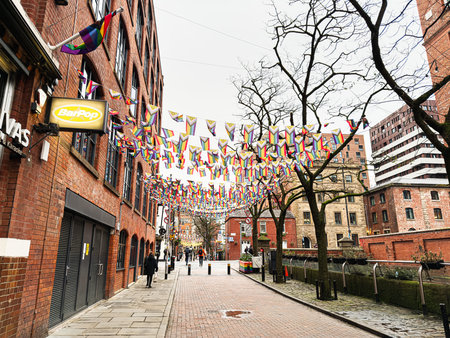 Manchester, UK - January 22, 2026: Colorful LGBT banners and flags over a brick street in...