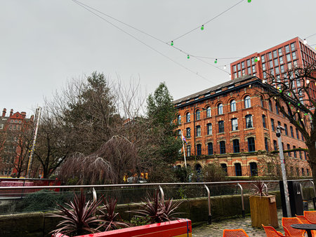 Manchester, UK - January 22, 2026: A city scene in Manchester featuring brick architecture, trees and festive string lights over outdoor seating.のeditorial素材