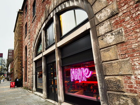 Manchester, UK - January 22, 2026: Urban scene in Manchester featuring red brick architecture and a bright pink Madre neon sign in a cafe window.のeditorial素材