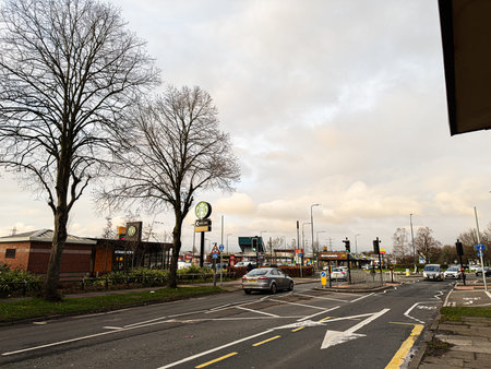 Manchester, UK - January 23, 2026: Urban street in Manchester with bare trees, cars and Starbucks fast food outlets along the road.のeditorial素材