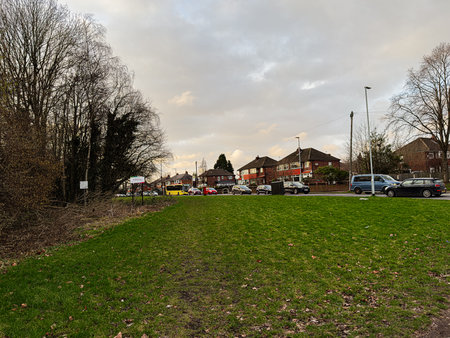 Manchester, UK - January 23, 2026: Green  Broadway park in a Manchester suburb, trees on the left, vehicles and houses along a road.のeditorial素材