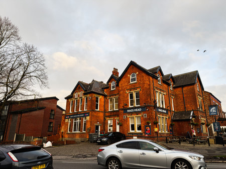 Manchester, UK - January 23, 2026: Quaint red brick Nags Head pubs along a cobbled street in...