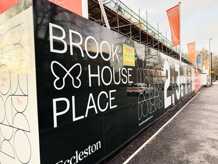 Manchester, UK - January 23, 2026: A long construction fence along a Manchester street displays large white lettering for Brook House Place and scaffolding in the background Eccleston Homes.のeditorial素材