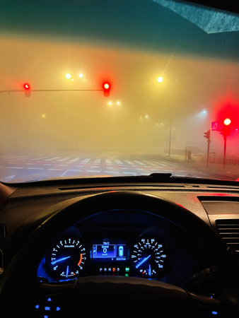 Nighttime drive through foggy streets with red signals and dashboard glow creating a moody urban...