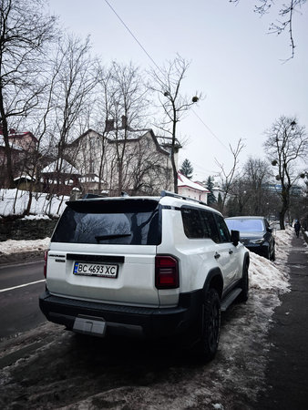 Lviv, Ukraine - February 07, 2026: A white Toyota Prado SUV parked along a snow-covered urban...