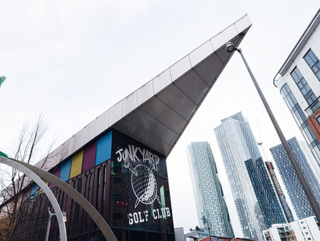 Manchester, UK - January 24, 2026: A stylish urban venue beside Junkyard Golf Club towering Manchester skyscrapers with a pitched roof.のeditorial素材