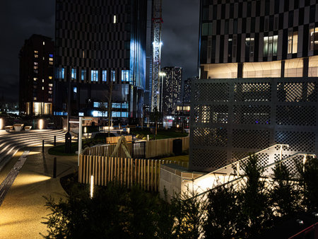 Nighttime cityscape in Manchester featuring contemporary architecture, construction crane, lit...