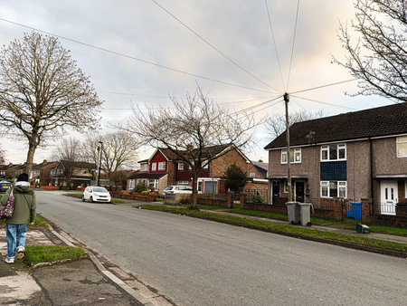 Quiet Manchester street scene with houses, cars, and pedestrians on a cloudy day.の写真素材