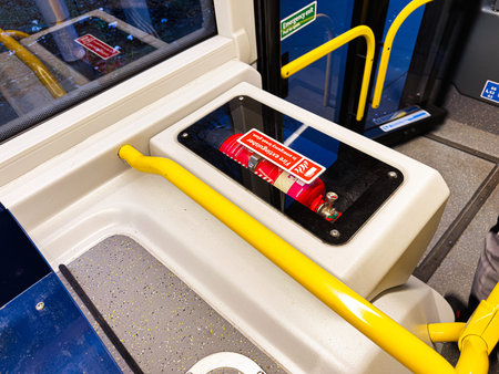 Public bus interior in Manchester showing a fire extinguisher and bright safety rails.