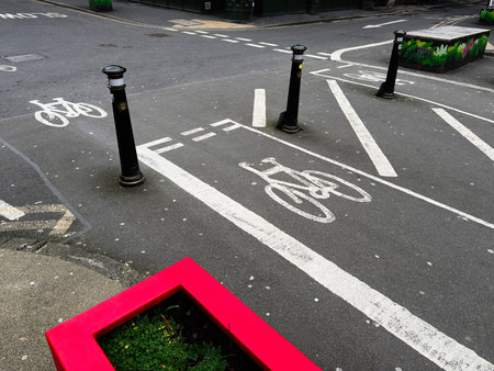 Vibrant Manchester street scene featuring bike lane markings, bollards, graffiti and a red planter.