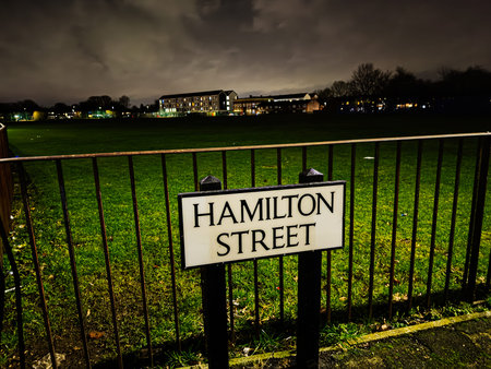 Street sign Hamilton Street beside a rail fence over a green park at night in Manchester.の写真素材