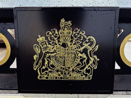 Gold coat of arms on a black pedestal in London, symbolizing monarchy, heritage, and tradition....