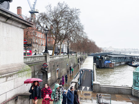 London, UK - February 01, 2026: Family and pedestrians walk along the wet Thames riverside under...