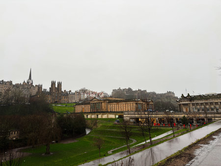 Rainy overcast panorama of Edinburgh Castle beside the National Gallery overlooking wet lawns and...