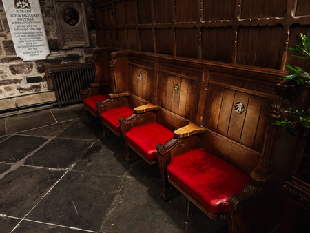Edinburgh, Scotland, UK - February 15, 2026: Row of carved oak benches with red seats in a dim stone St Giles church interior in Edinburgh.のeditorial素材