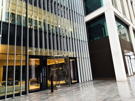 Illuminated lobby seen through a glass facade of a modern office building in London, UK business district.のeditorial素材