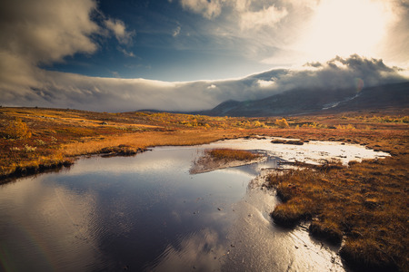 Vast landscapes near Sylan mountains. Norwegian autumn. Small lake reflections. Heavy clouds and...