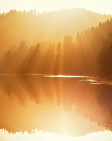 Morning sun light in foggy air. Water reflections of Litlvatnet lake and autumnal colours. Norwegian autumn.の写真素材