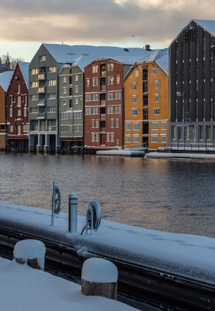 Old wooden buildings, magazines, by the shores of Nidelva river, winter time in Trondheim, Norway.の写真素材
