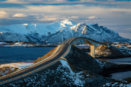 Atlantic Ocean Road - Atlanterhavsvegen in winter sunny day. Famous high bridge over the sea called Storseisundbrua and beautiful snowy mountains in a horizon.の写真素材