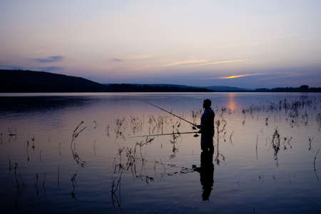 Fishing spinning at sunset. Silhouette of a fishermanの写真素材