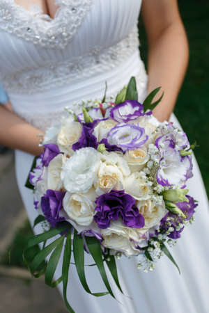 Close up of a bride holding a purple bouquet.の写真素材
