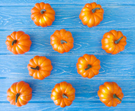 On a bright blue wooden background there are plastic bright orange pumpkinsの写真素材