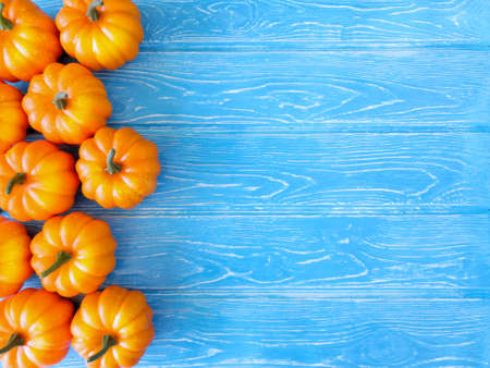 On a bright blue wooden background there are plastic bright orange pumpkinsの写真素材