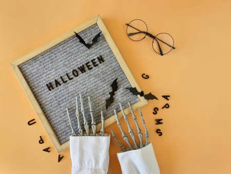 the skeletons hands lay out the word Halloween in a wooden frameの写真素材
