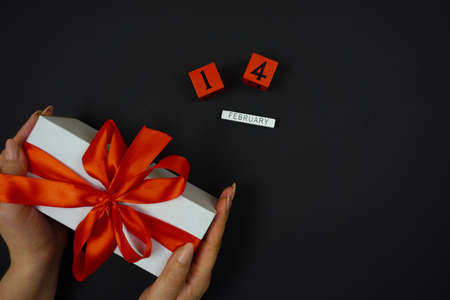 a womans hands hold a white gift with a red bow on February 14の写真素材