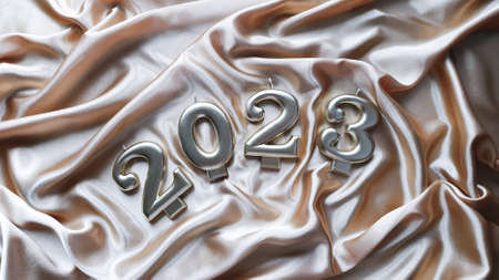 Candles in the form of numbers 2023 are lying on a golden silk fabricの写真素材