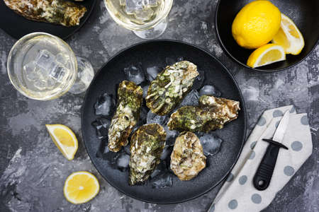 The festive table is served with black dishes with fresh oysters