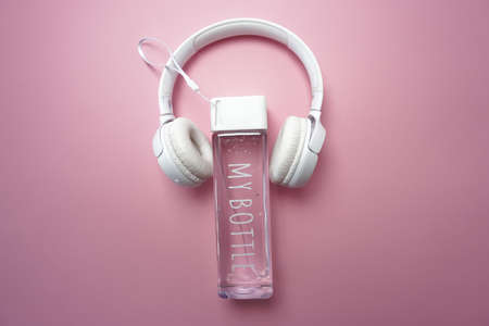 On a pink background is a bottle of water and headphonesの写真素材