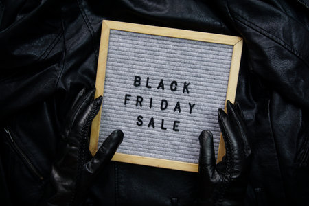 Hands in black gloves hold a frame with the inscription - Black Friday saleの写真素材