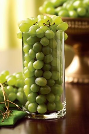 Green grapes in glass on wooden table, close-up, verticalの素材