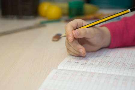 Book is on the table, the boy is doing homeworkの写真素材